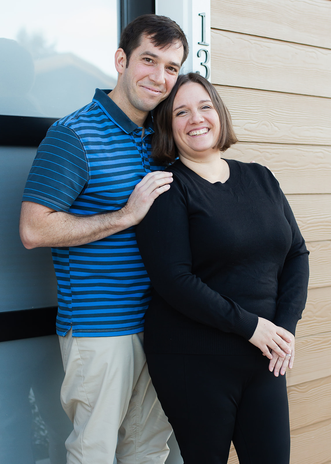 A couple posing in front of the door to their new townhome.