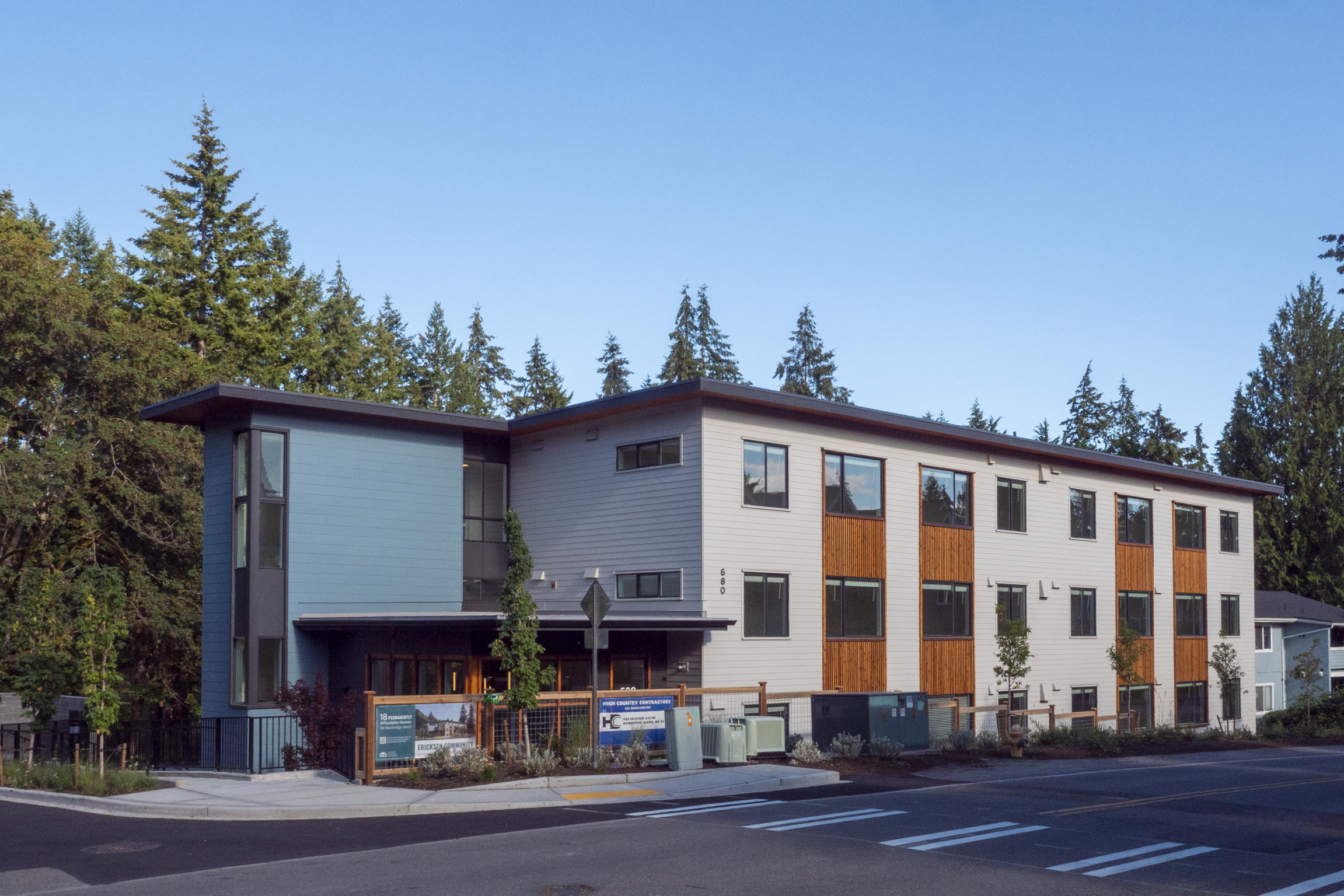Two story-apartment building with blooming trees in the courtyard.
